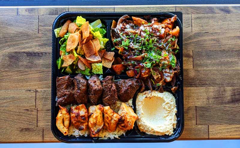 a combination plate of meat, hummus and salad