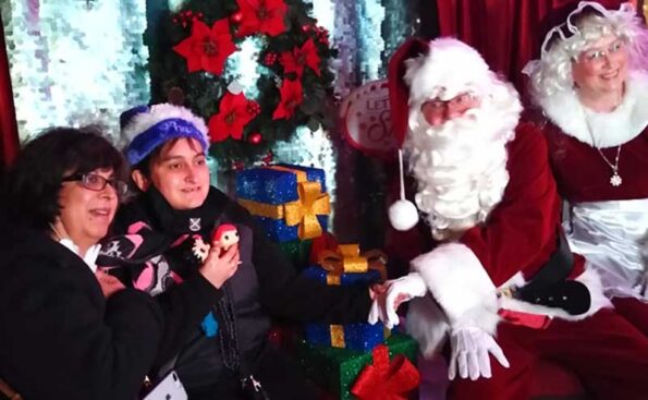 A girl with her mom meeting Santa and Mrs Claus