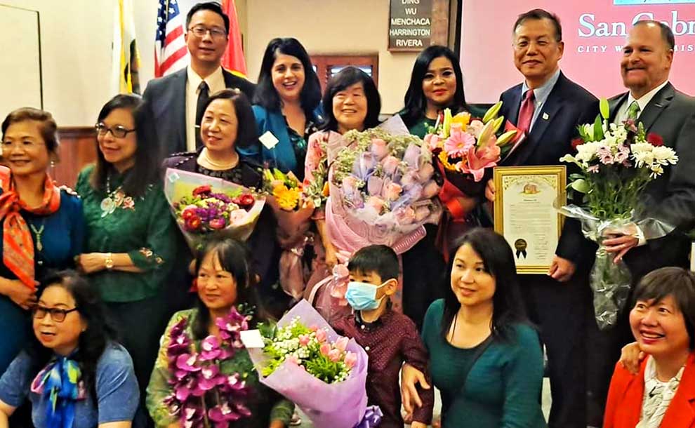 A woman holding flowers surrounded by people