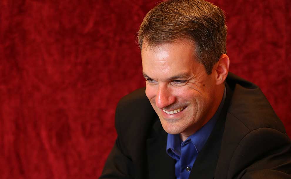 A man leaning on a piano laughing