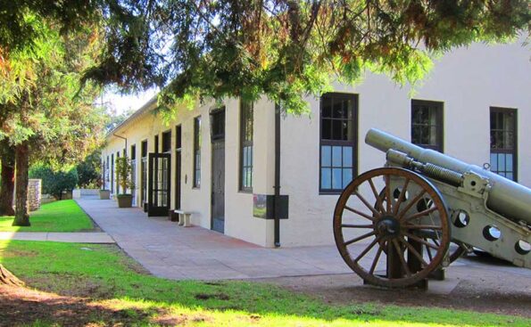 An old building with a cannon on the lawn
