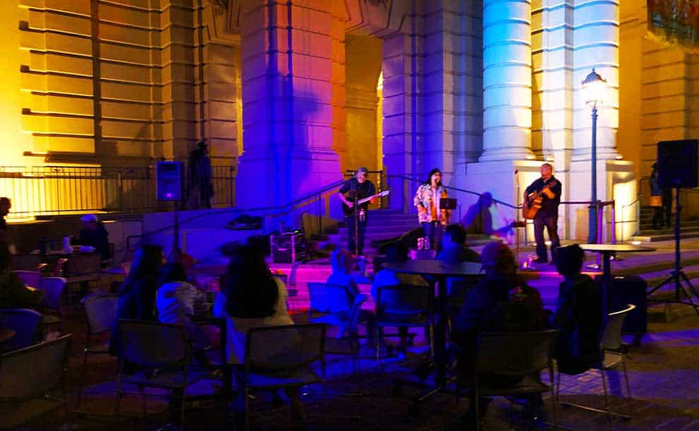 musicians playing on steps of a building with people listening