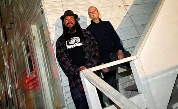 two men posing by the stairs of an old building