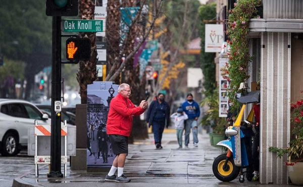 A man taking a photo of a shop on the street
