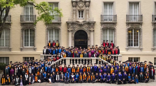 students standing by stairs in colorful caps and gowns