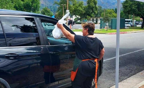 a woman hand a bag to a car