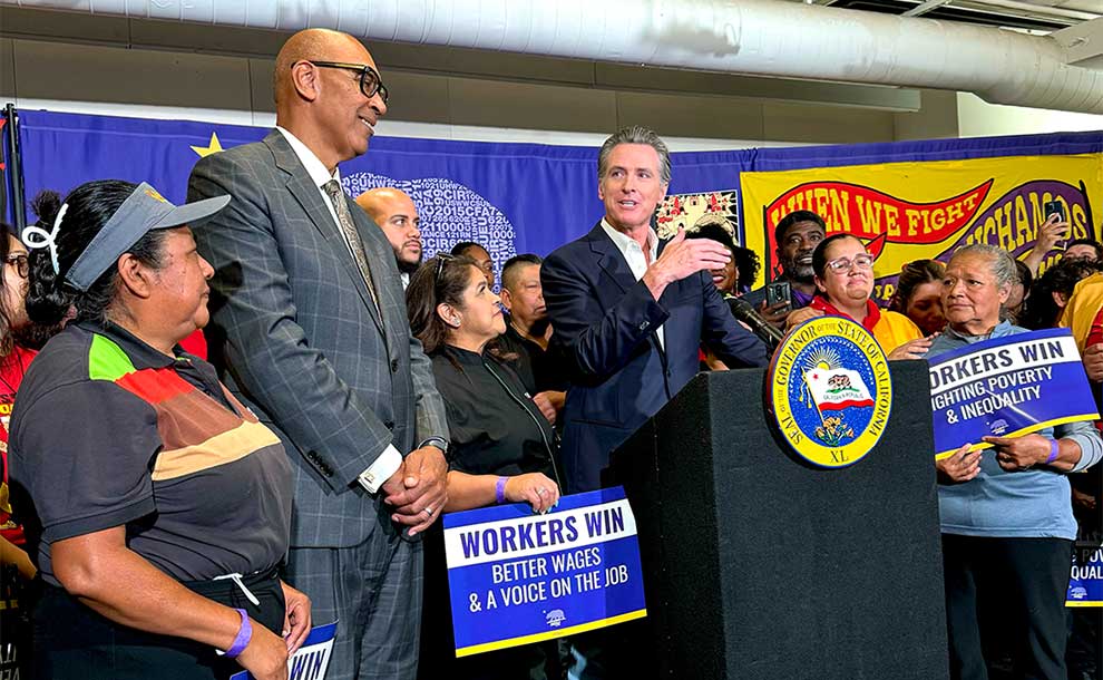 person at a podium surrounded by workers