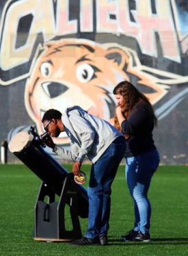 Two people looking into a telescope