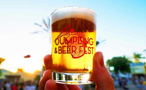 A hand holding a glass of beer