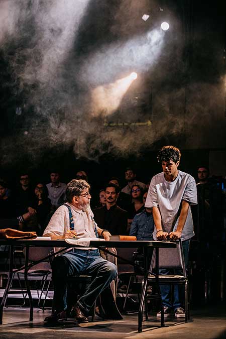 a man sitting on a table and a young man standing