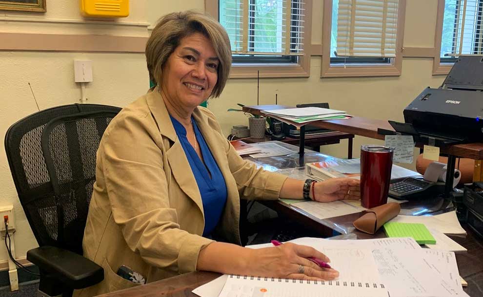 a woman behind her desk smiling