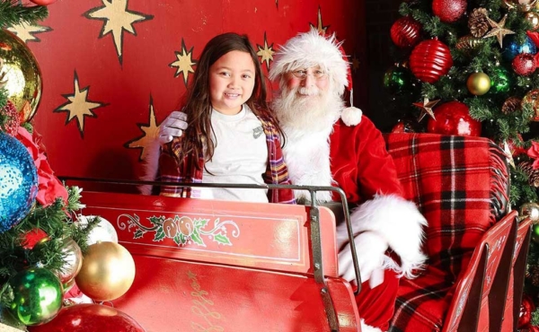 A girl smiling next to Santa