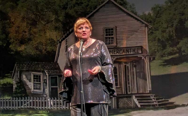 a woman standing in front of a projection of an old house