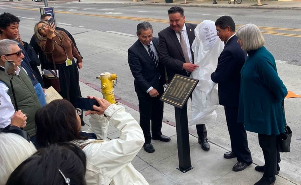 officials unveil a plaque on the sidewalk