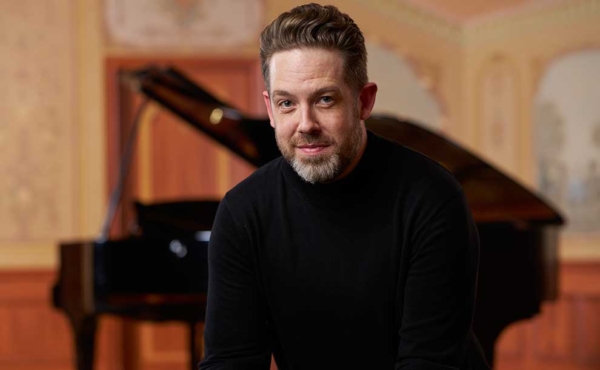 a man sitting next to a piano smiling