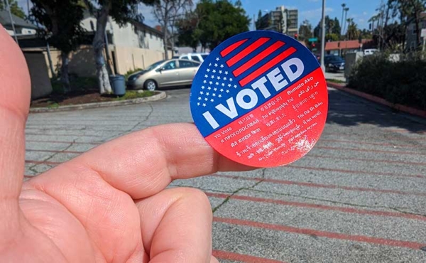 a hand holding a sticker that says "I voted"
