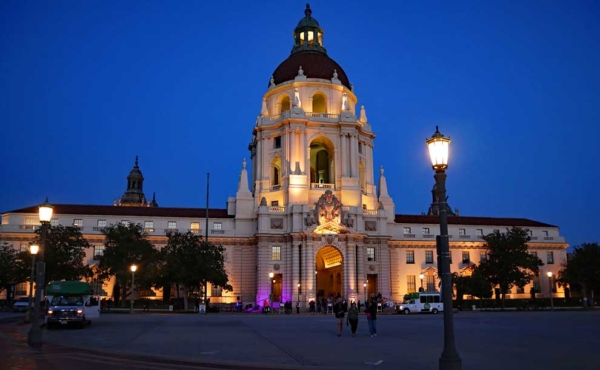 a grandiose building with buses and people walking by