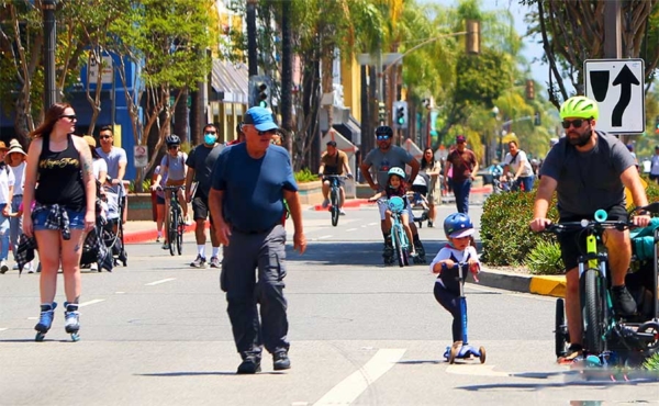 people on the street biking, skateboarding and walking
