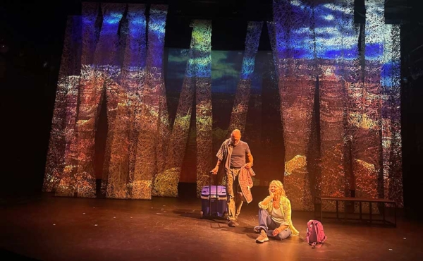 a man and a woman in a projected forest on columns behind them