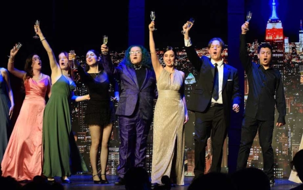 students on stage raising their glasses up in the air