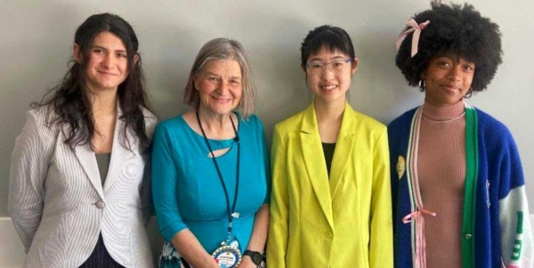 three girls standing next to a woman smiling at camera