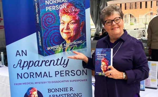 A woman standing by a cut out of her book next to her