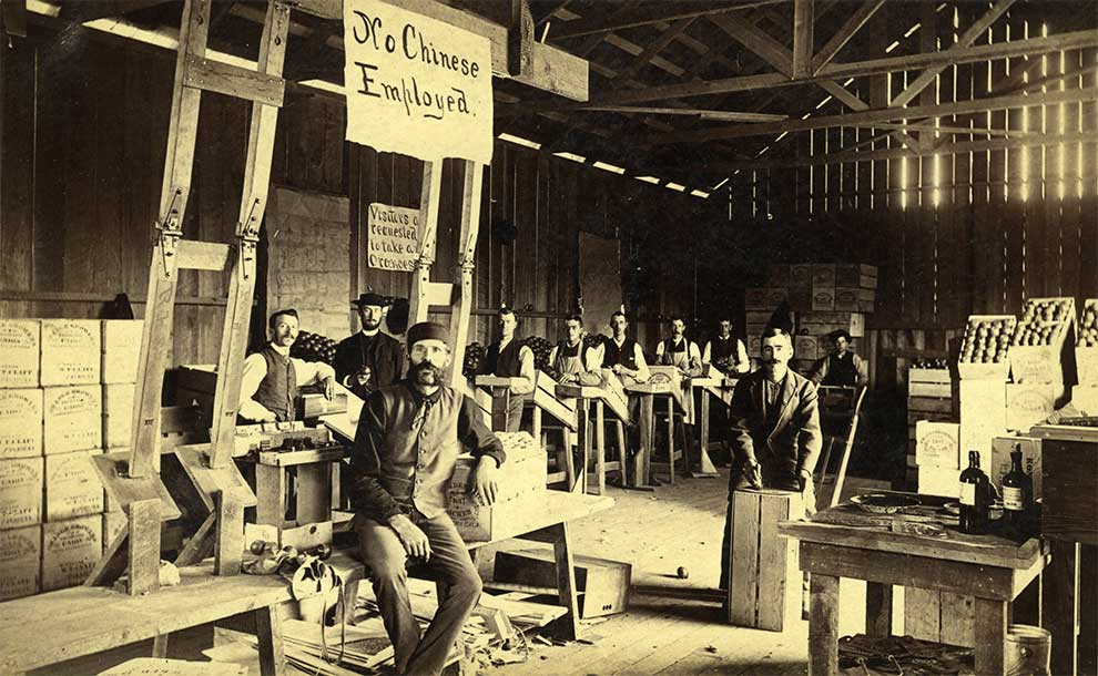 An old photo of a warehouse with a sign proclaiming no Chinese employed