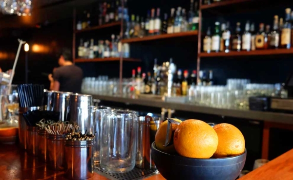 an interior of a bar with stools, glasses and a bowl of lemons