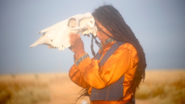 A person holding an animal skull to their head