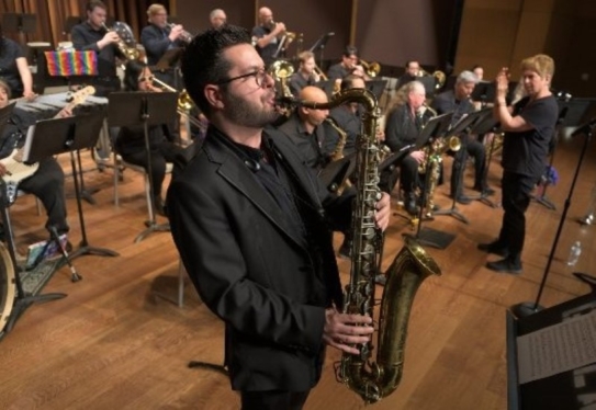A man playing saxophone surrounded by other musicians