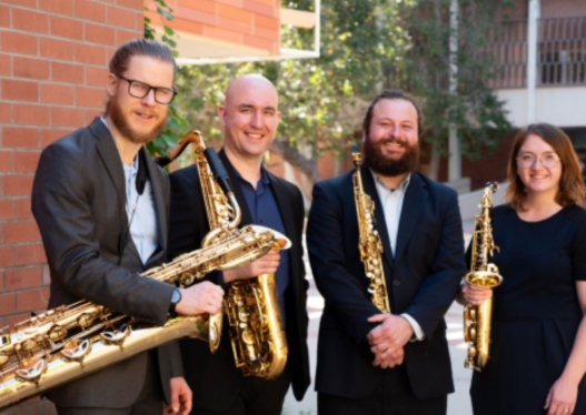 Four people holding saxophones