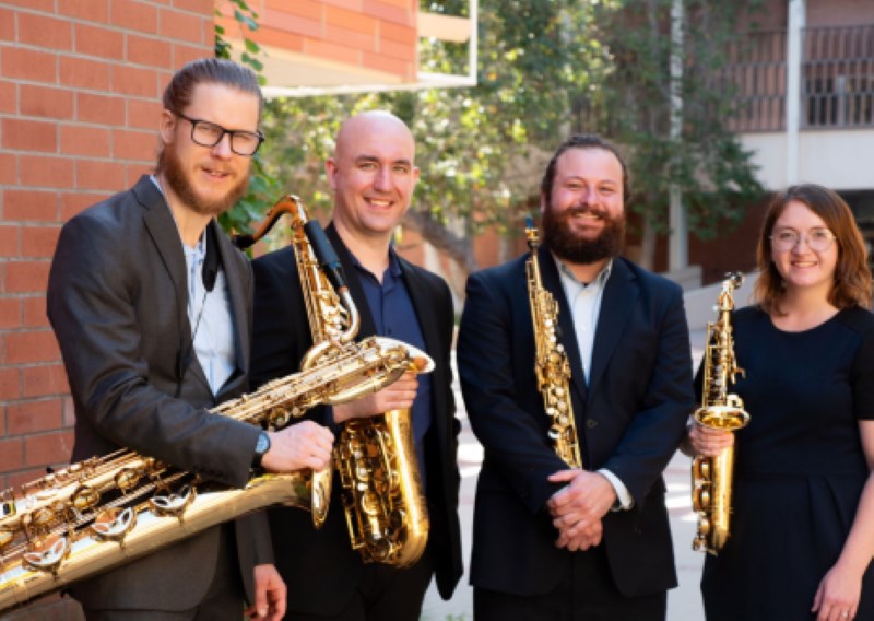 Four people holding saxophones