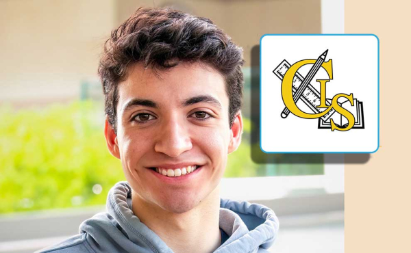 A kid smiling with a logo of his school next to him
