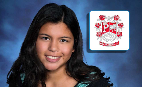 A girl smiling next to her school logo