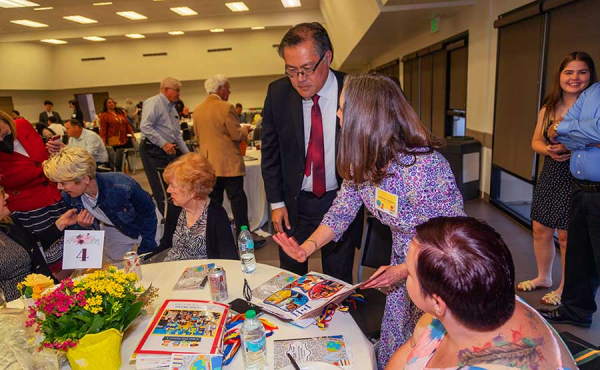 A teacher showing a man photos at a banquet