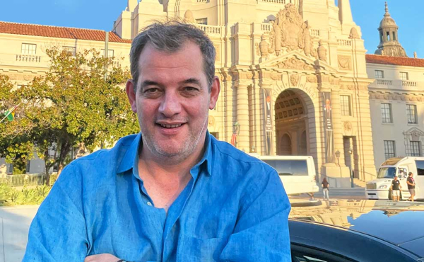A man smiling in front of a majestic building