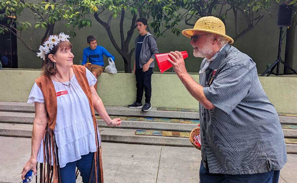 A man dressed as a movie director directing a starlet