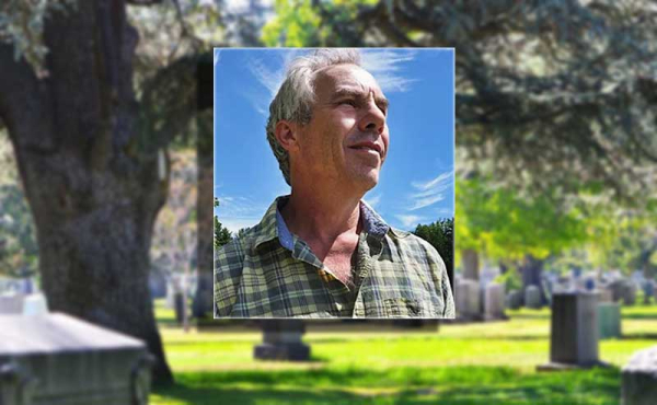 a man looking upward and headstones behind him