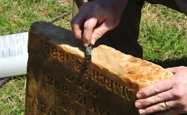 a man repairing a headstone with a filer