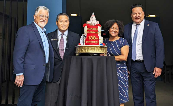 People standing behind a cake smiling