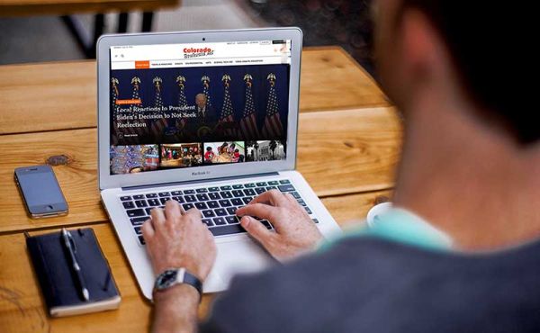 a man typing on a laptop showing Colorado Boulevard screen