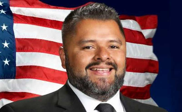 A man smiling with American Flag behind him