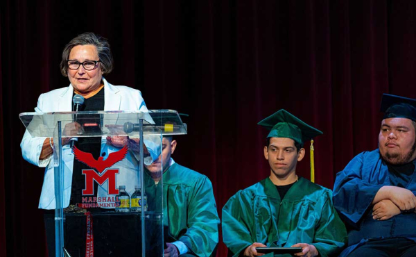 a person on stage behind podium with students in the background
