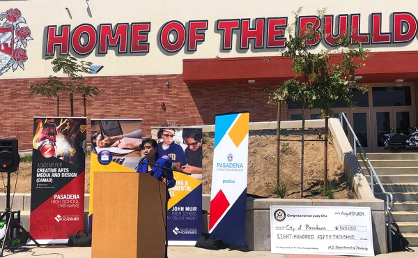 a woman speaking next to an oversized check