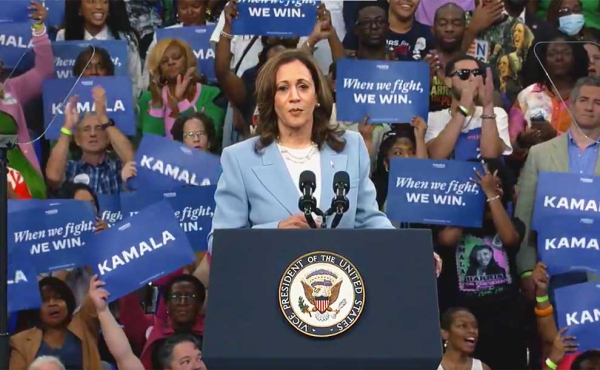 A woman speaking behind a podium at a rally