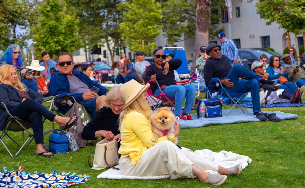 A woman holding a pet and people sitting at a park