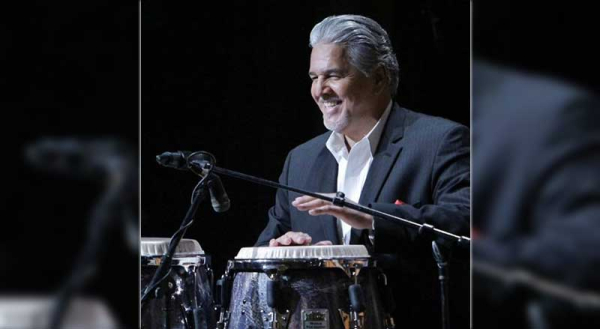 A man smiling and hitting drums