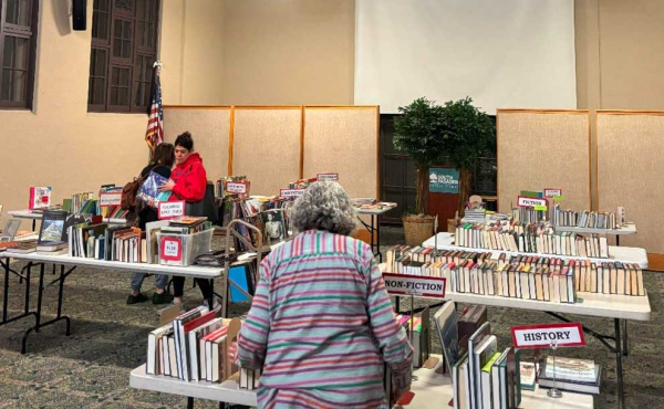 a woman looking at a table filled with books