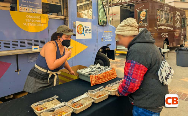 a woman handing out sandwiches