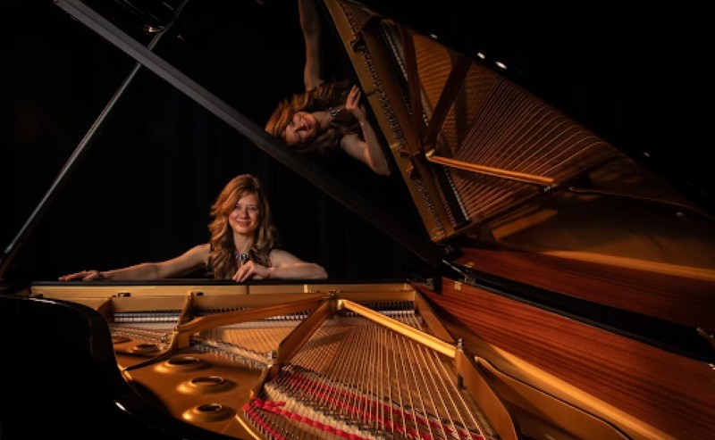 A woman smiling by a piano